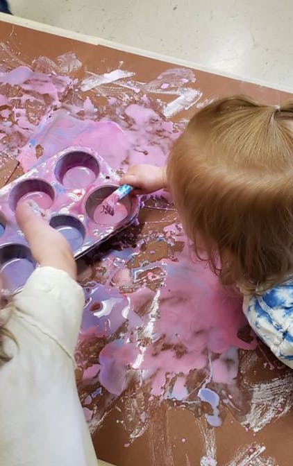 Child playing with paint in a muffin tin