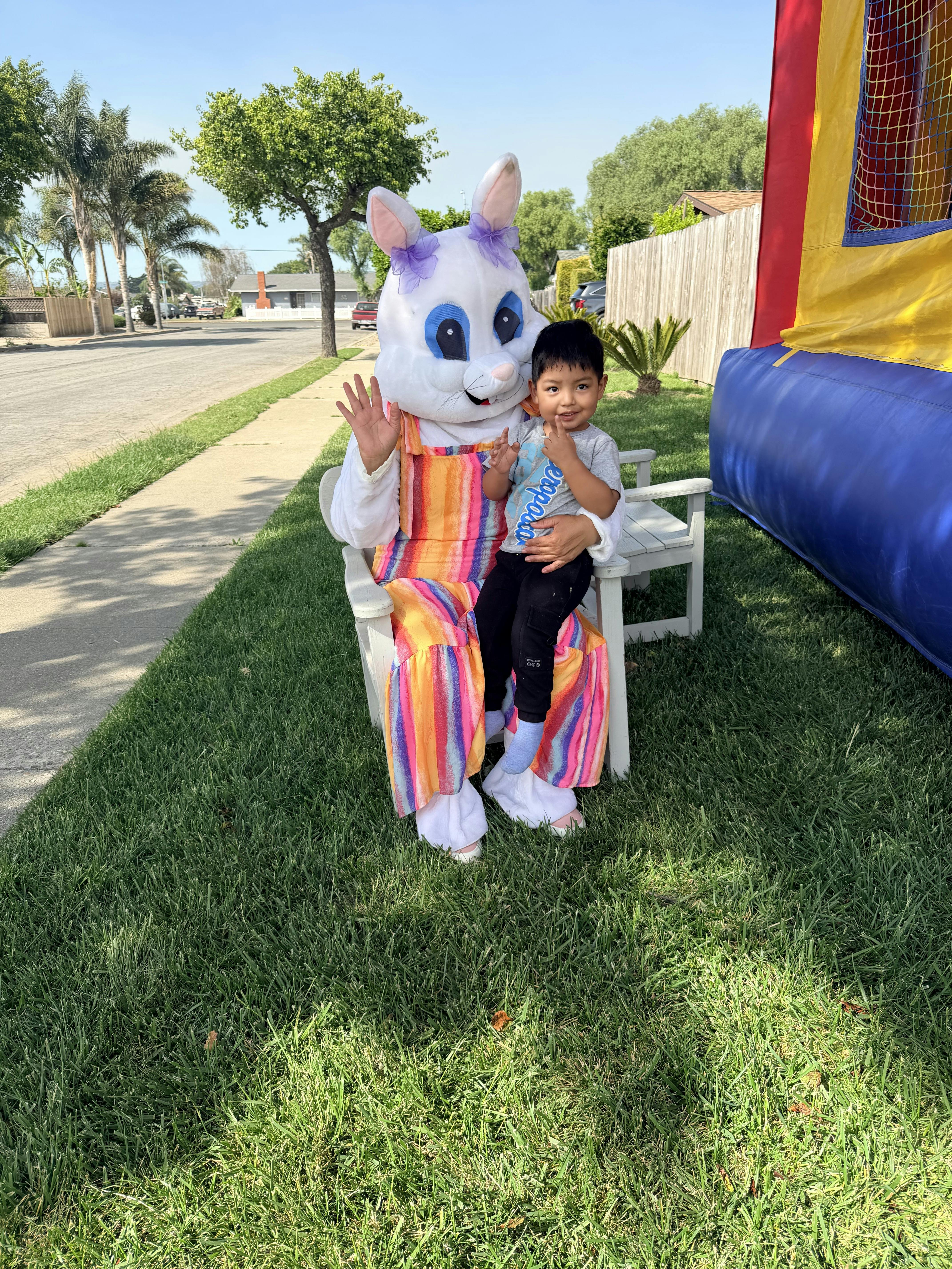 Child sitting on the lap of a person in an Easter bunny costume