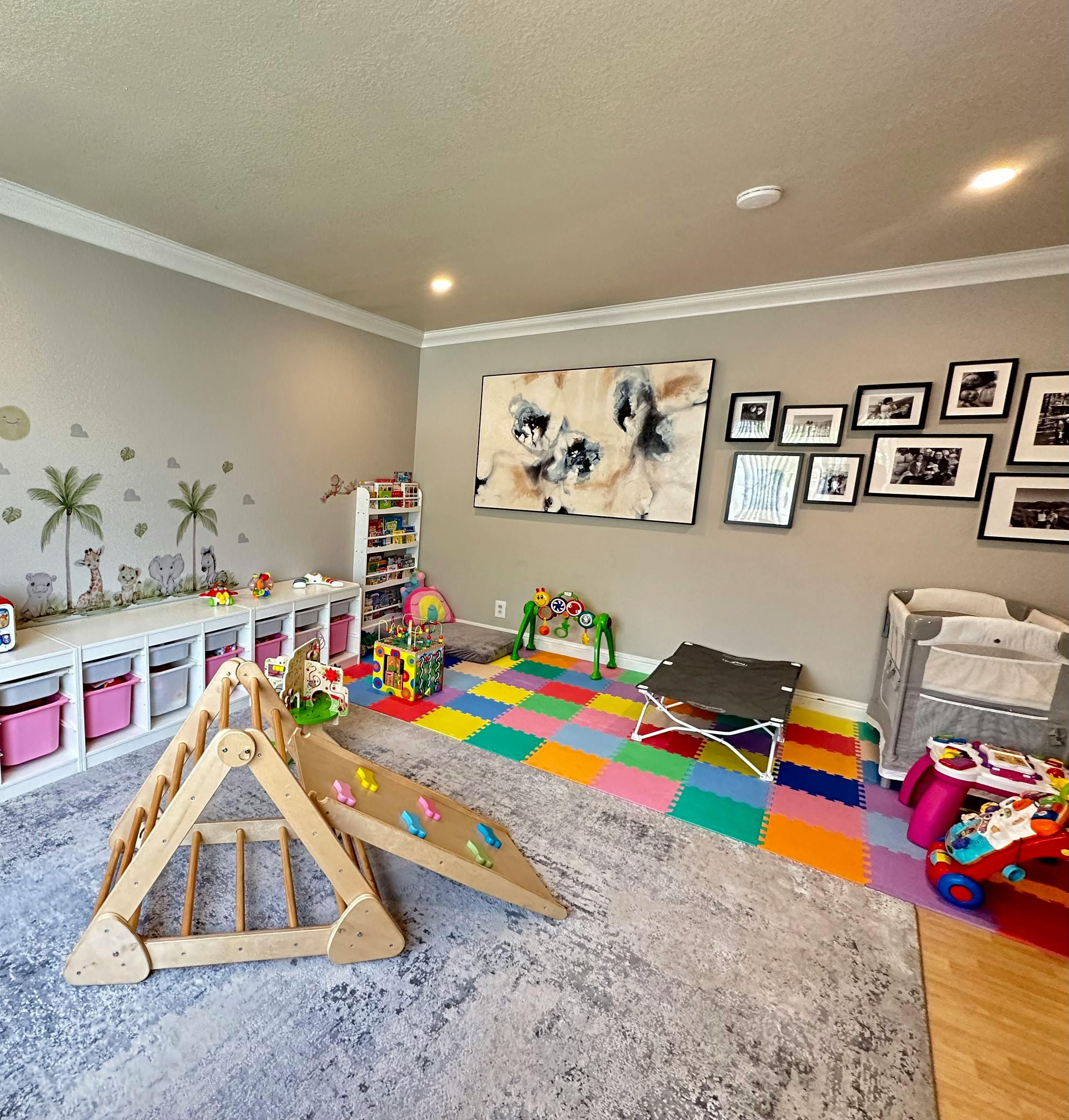 Playroom with a wooden climbing structure, colorful floor mats, and toys