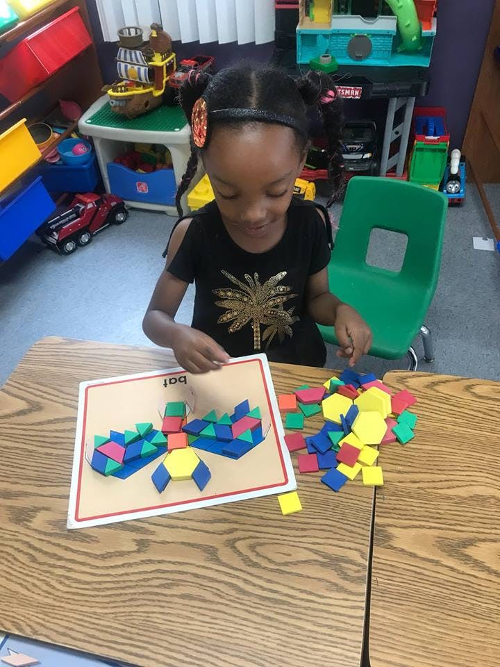 Child playing with colorful geometric shape blocks at a table