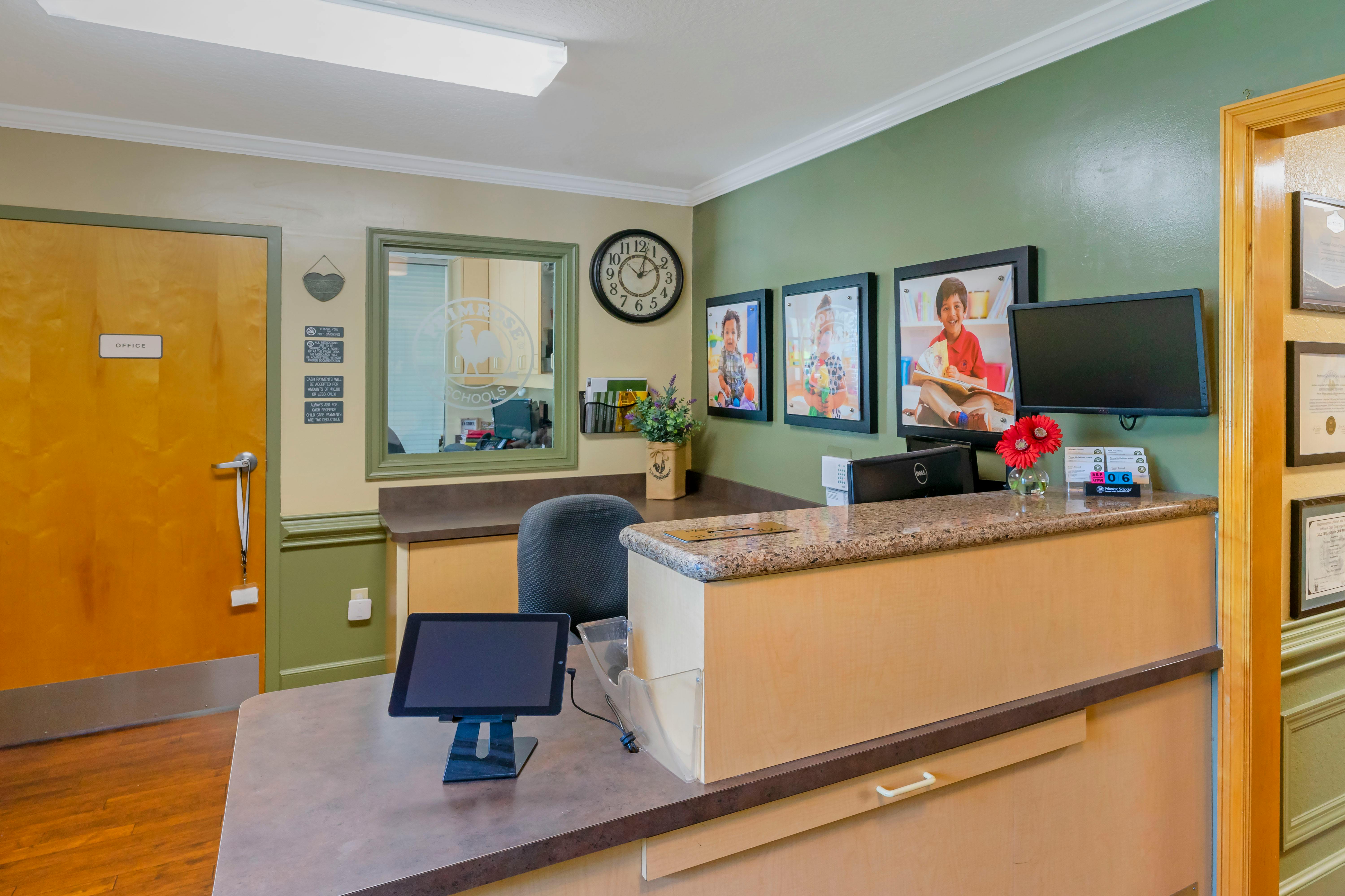 Reception desk with an office door, pictures of children, and a window