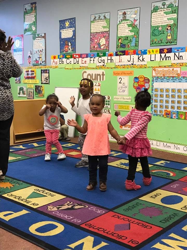 Four children and an adult in a classroom