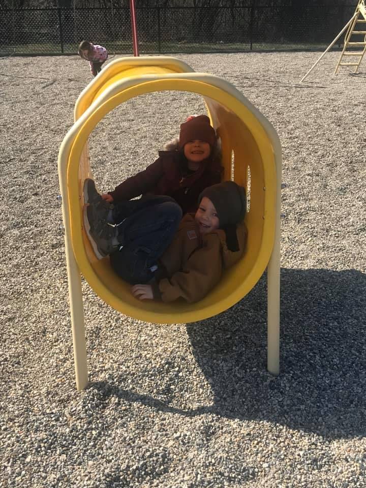 Two children in a yellow tunnel on a playground