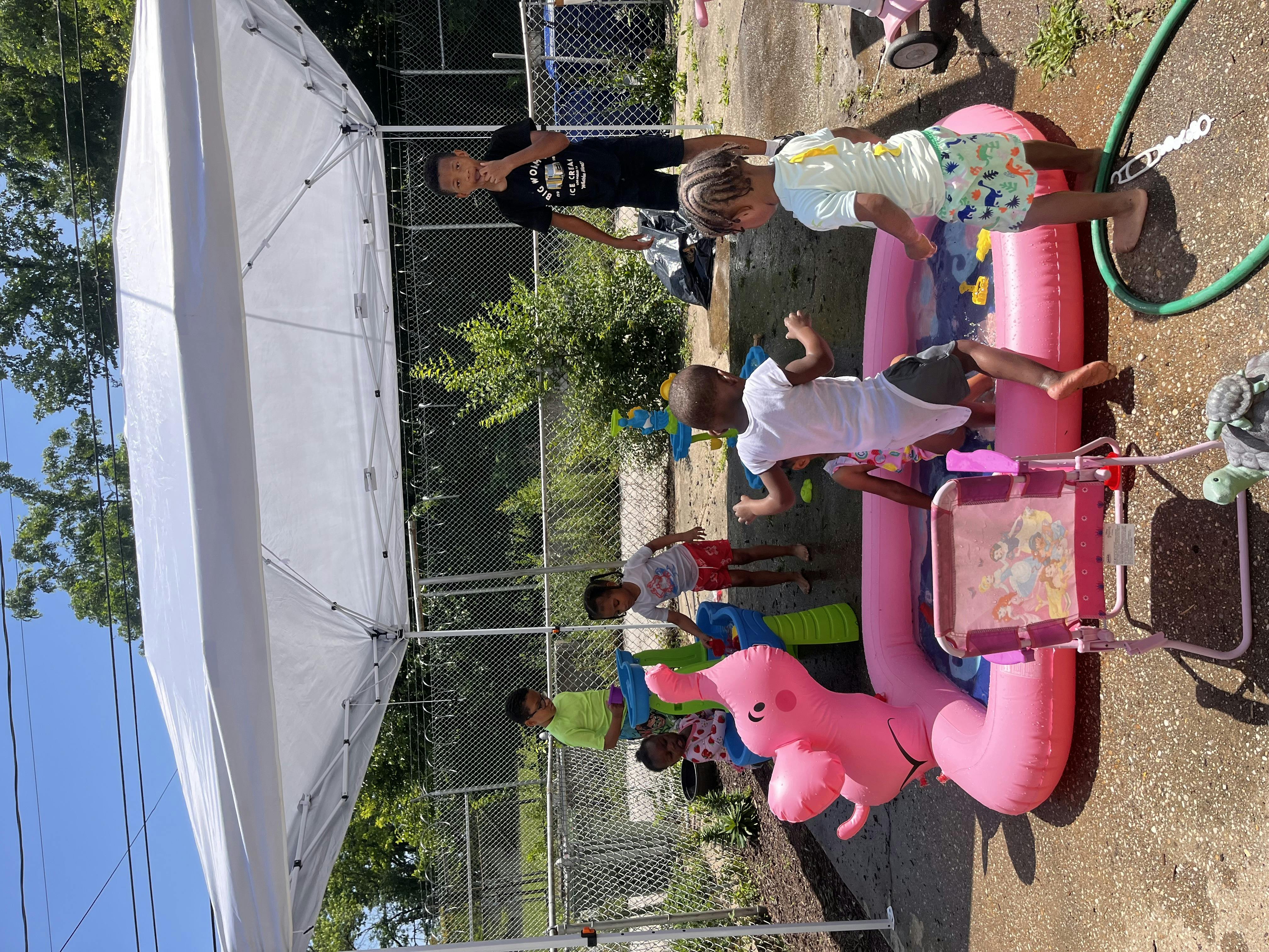 People and children playing with water in an inflatable pool