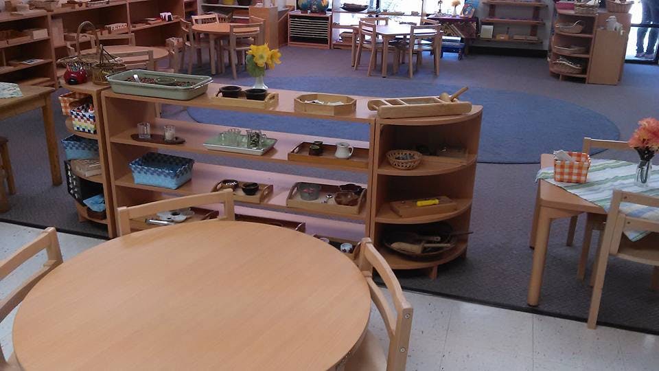 Classroom with small tables and shelves of learning materials