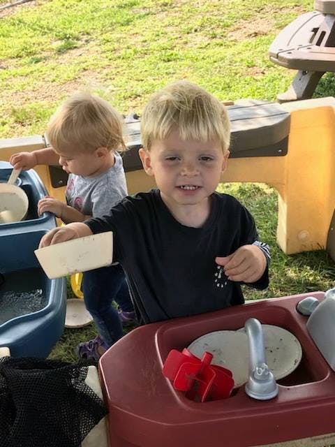 Two children playing with water tables outdoors