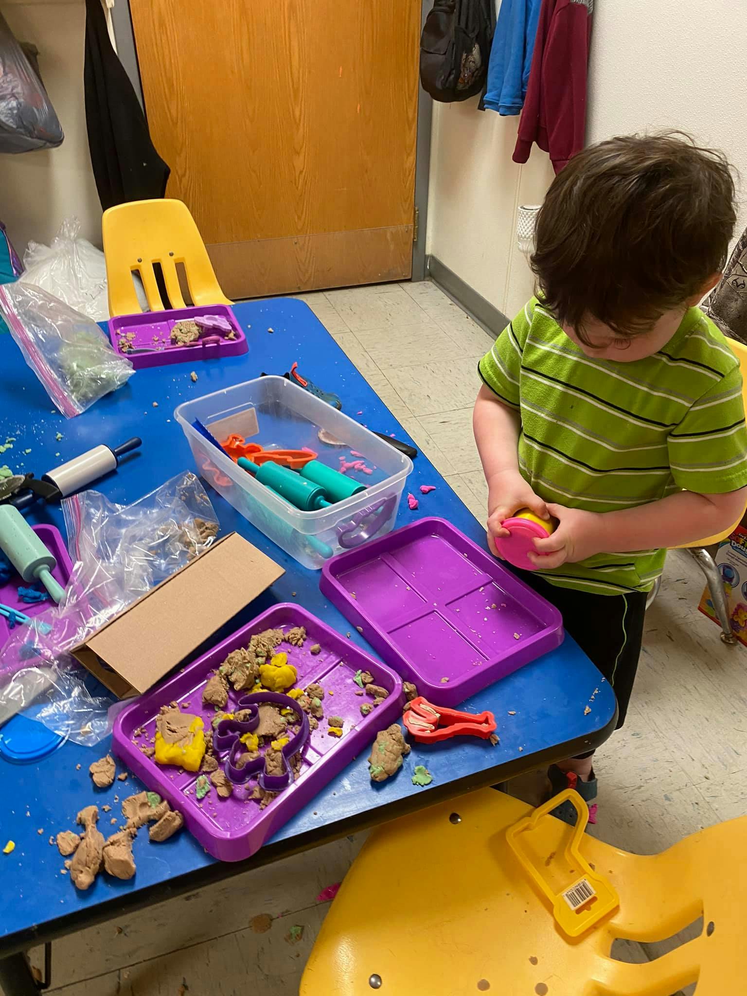 Child playing with kinetic sand at a blue table