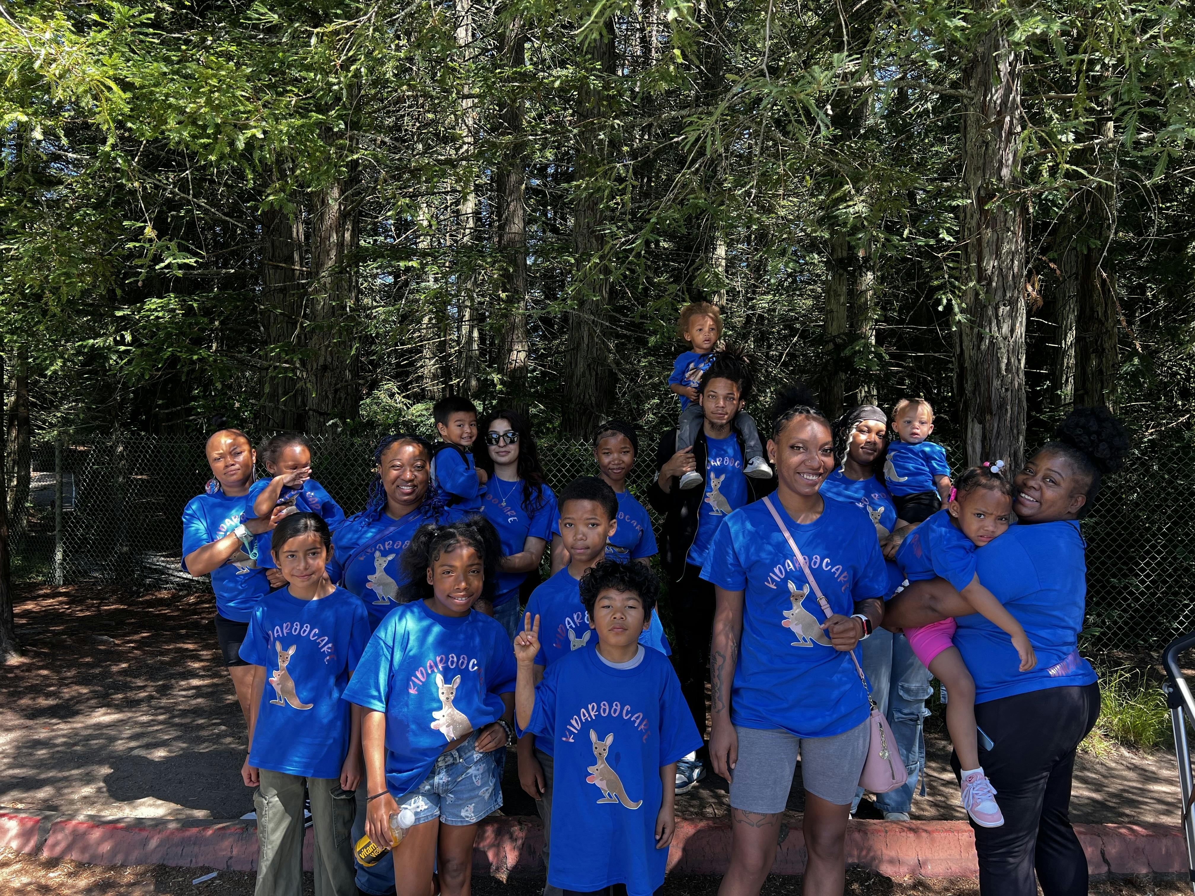 Group of people and children in blue shirts posing outdoors