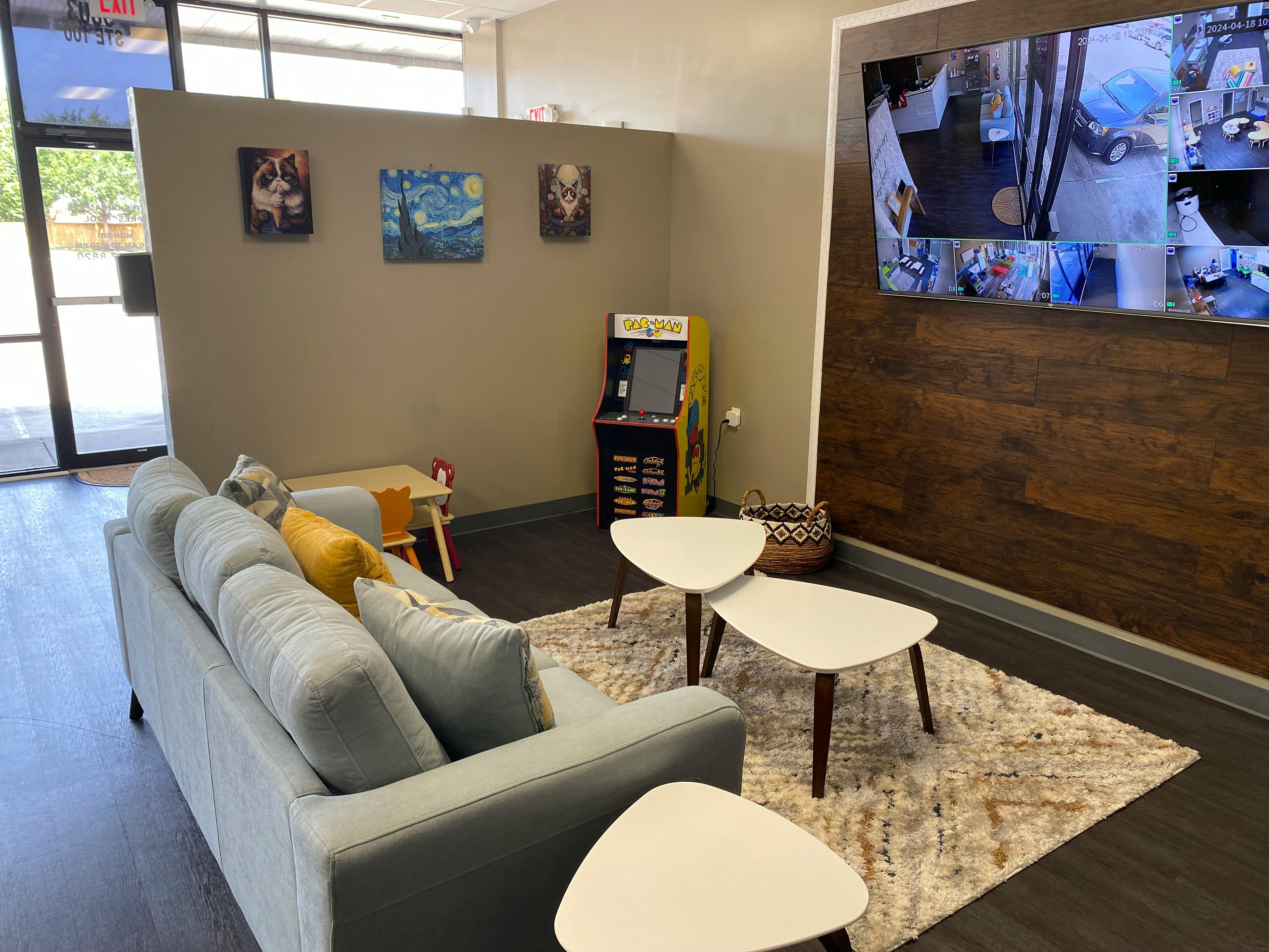 Lounge area with a sofa, coffee tables, and a large screen on the wall