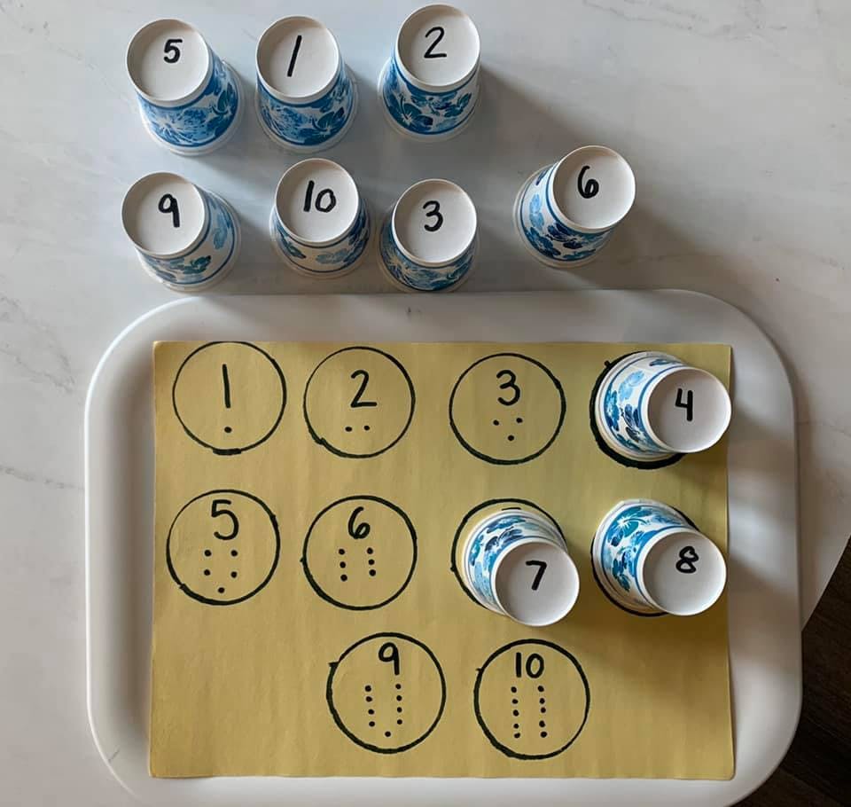 Paper cups with numbers 1-10 and a board with corresponding dots for counting