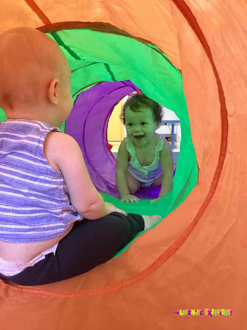 Two children playing in a colorful tunnel