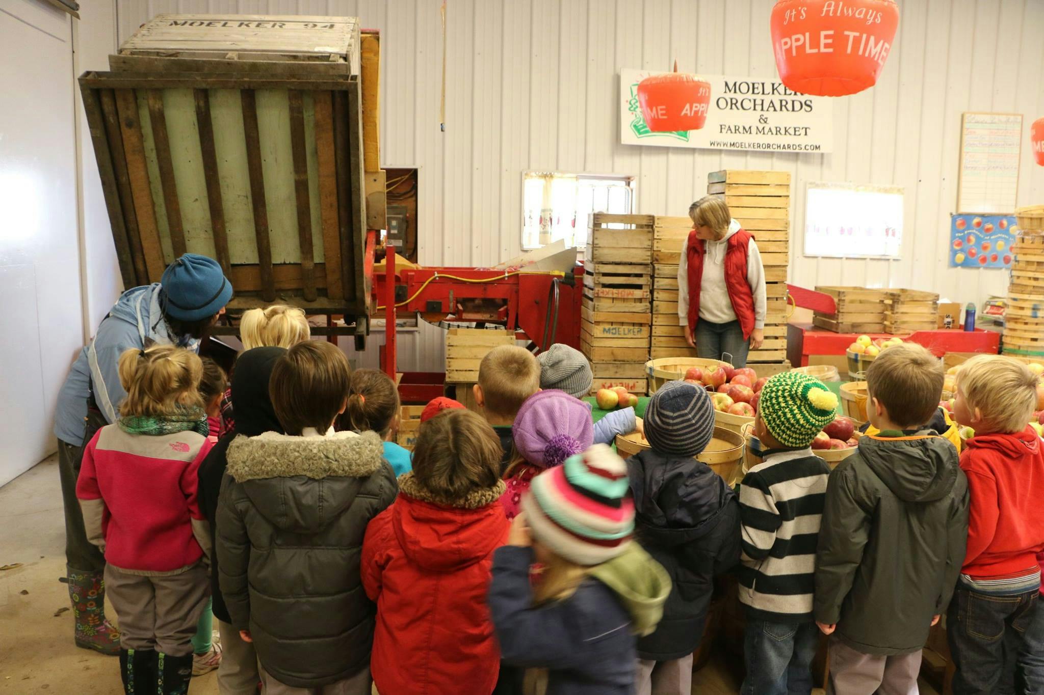Adults and children gathered around a machine in an indoor space