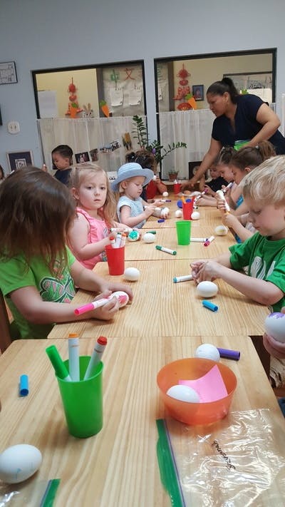 Children and an adult decorating eggs at a table