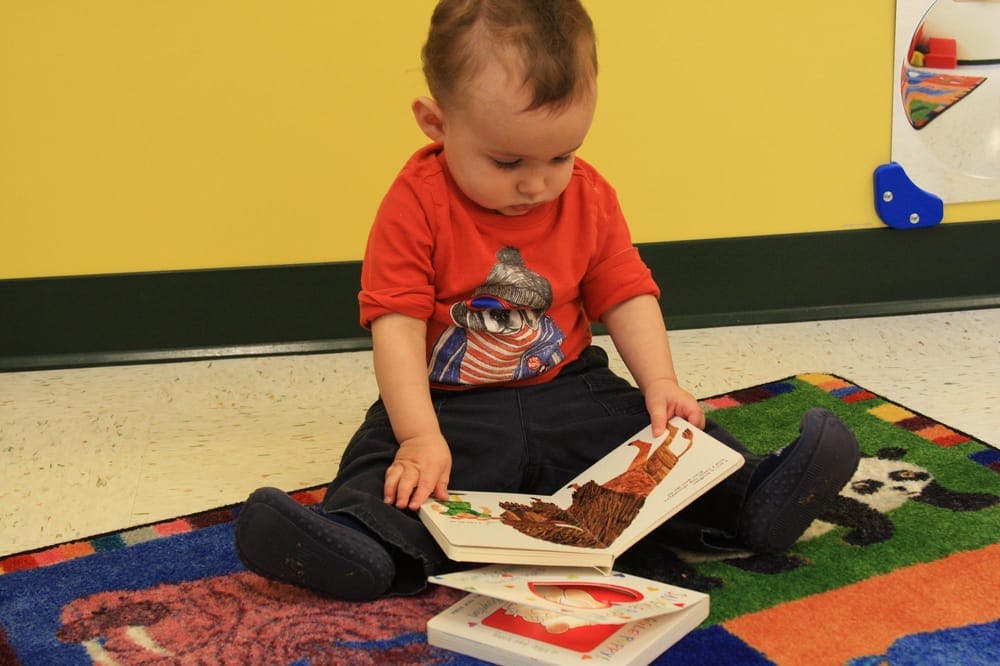 Child sitting on a rug looking at a book