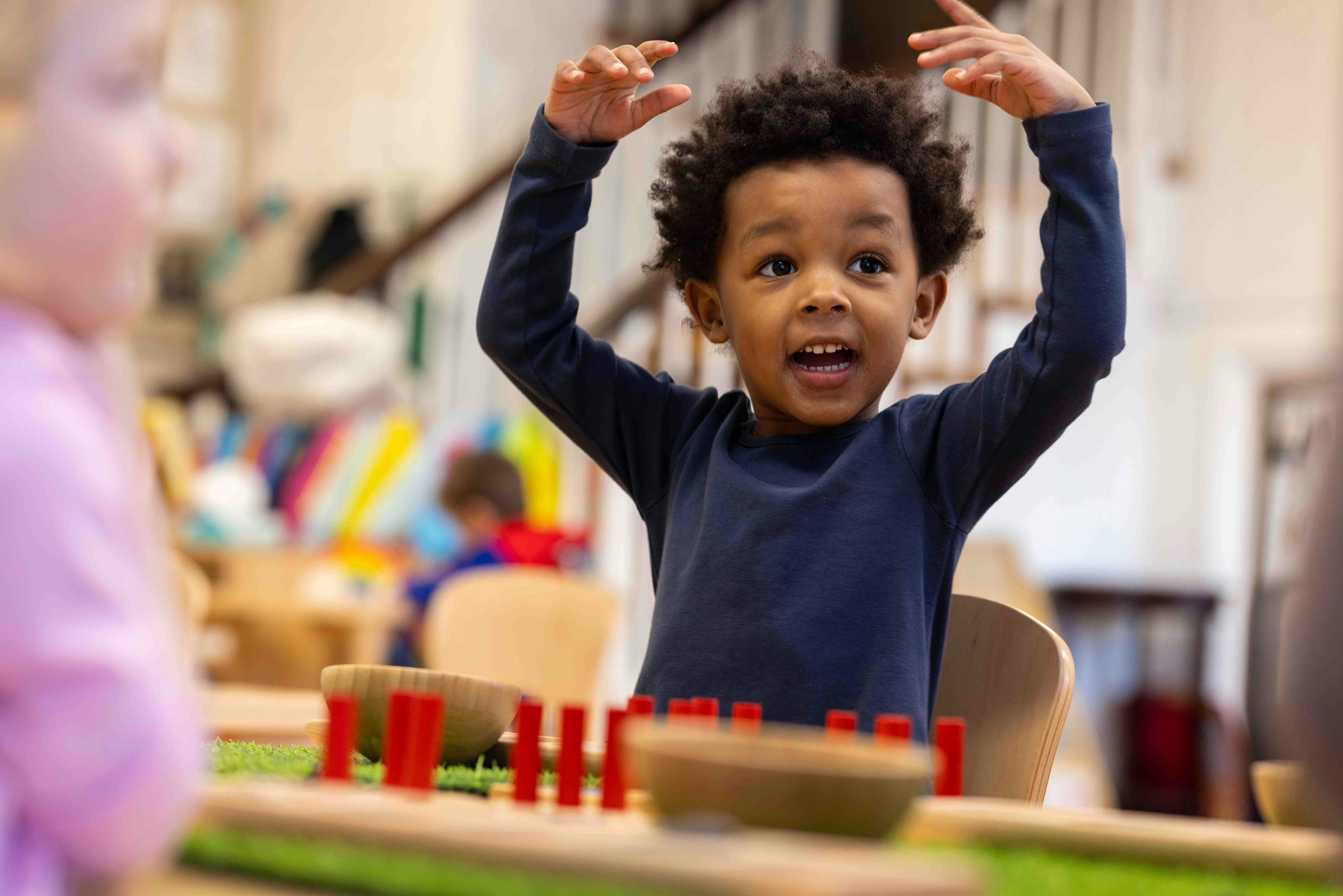 Child with hands raised above head, mouth open