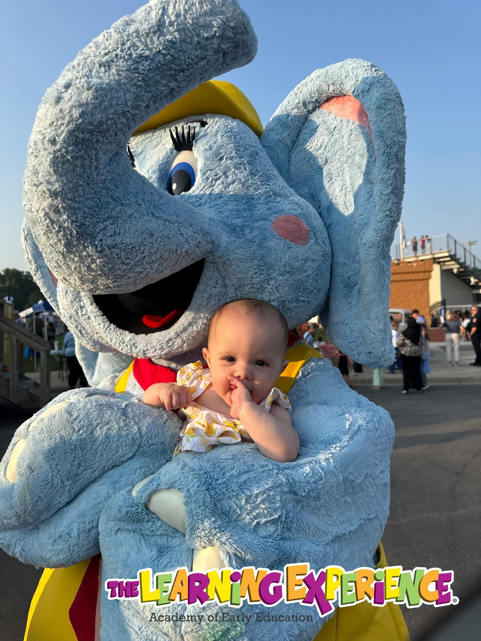 Child sitting in the arms of a person in an elephant costume
