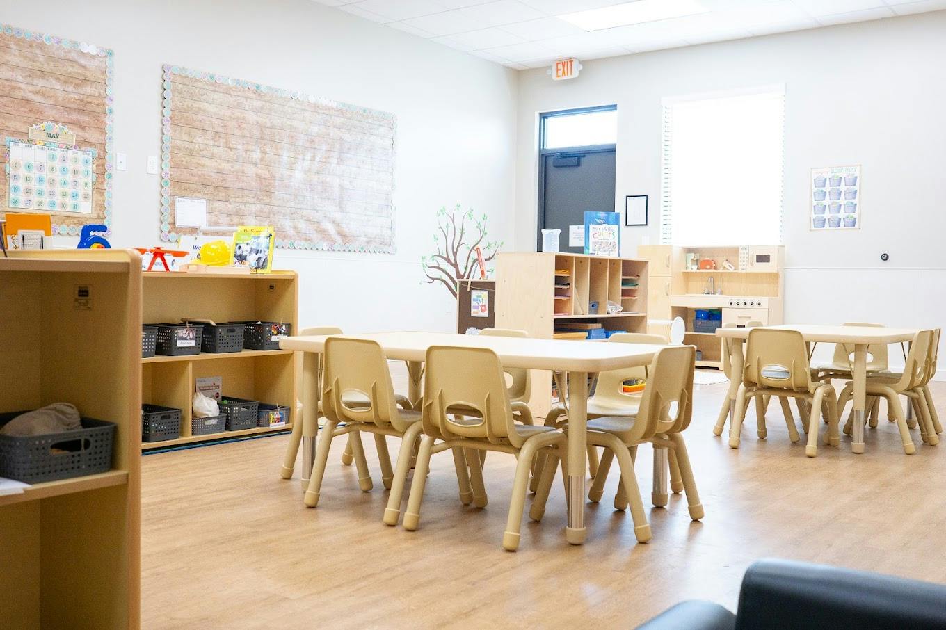Empty preschool classroom with small tables and chairs