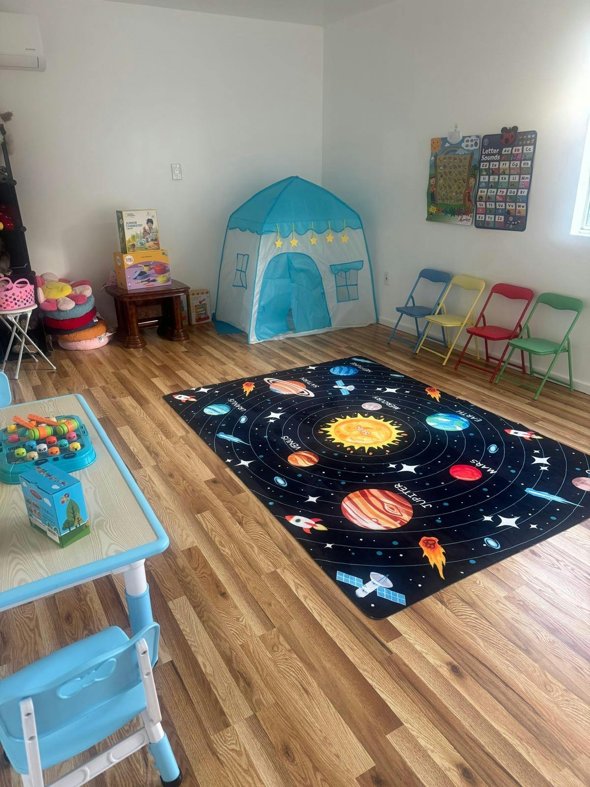 Playroom with a solar system rug, blue play tent, and child-sized table and chairs
