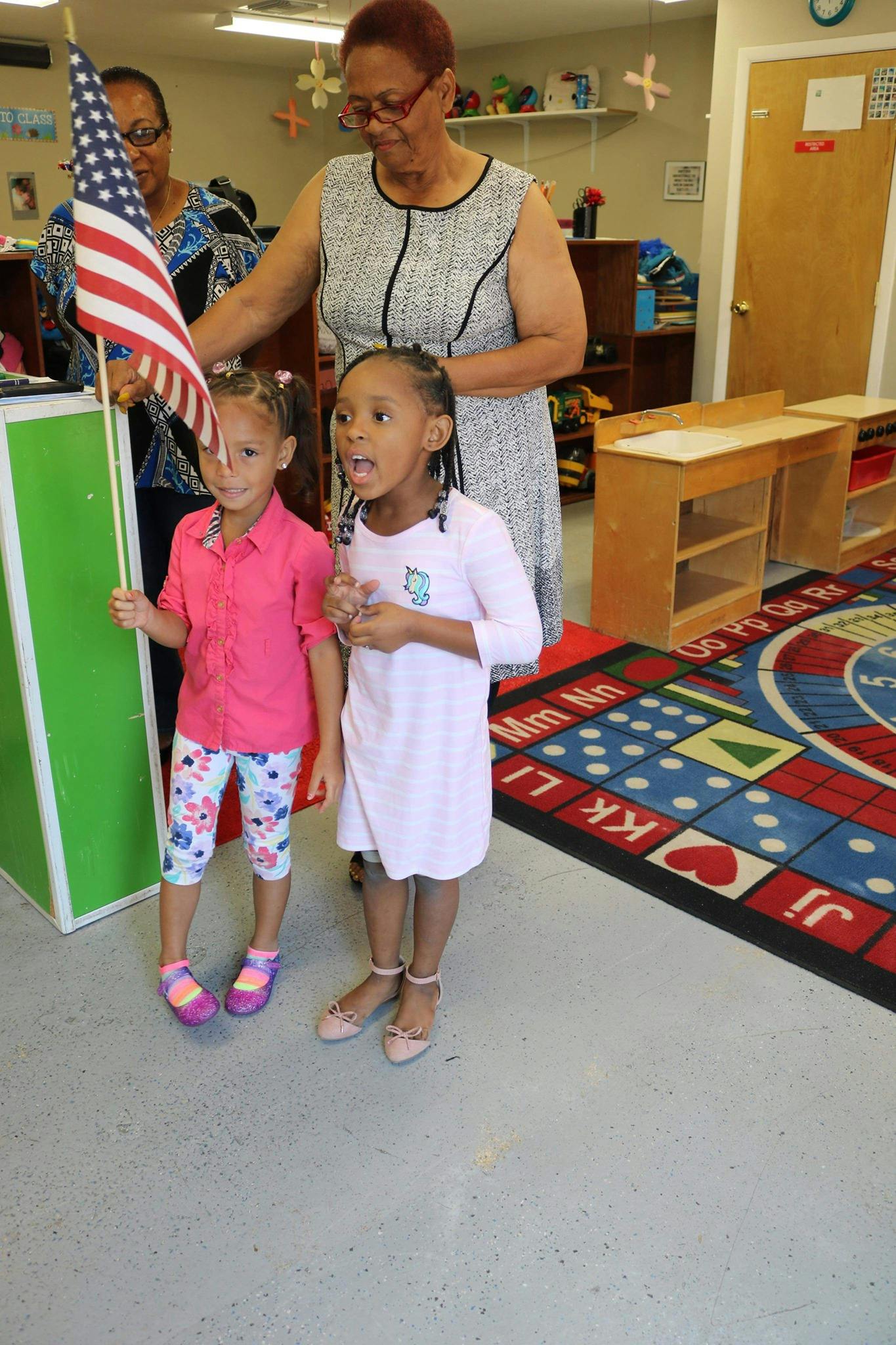 Adult and two children standing, one child holding an American flag