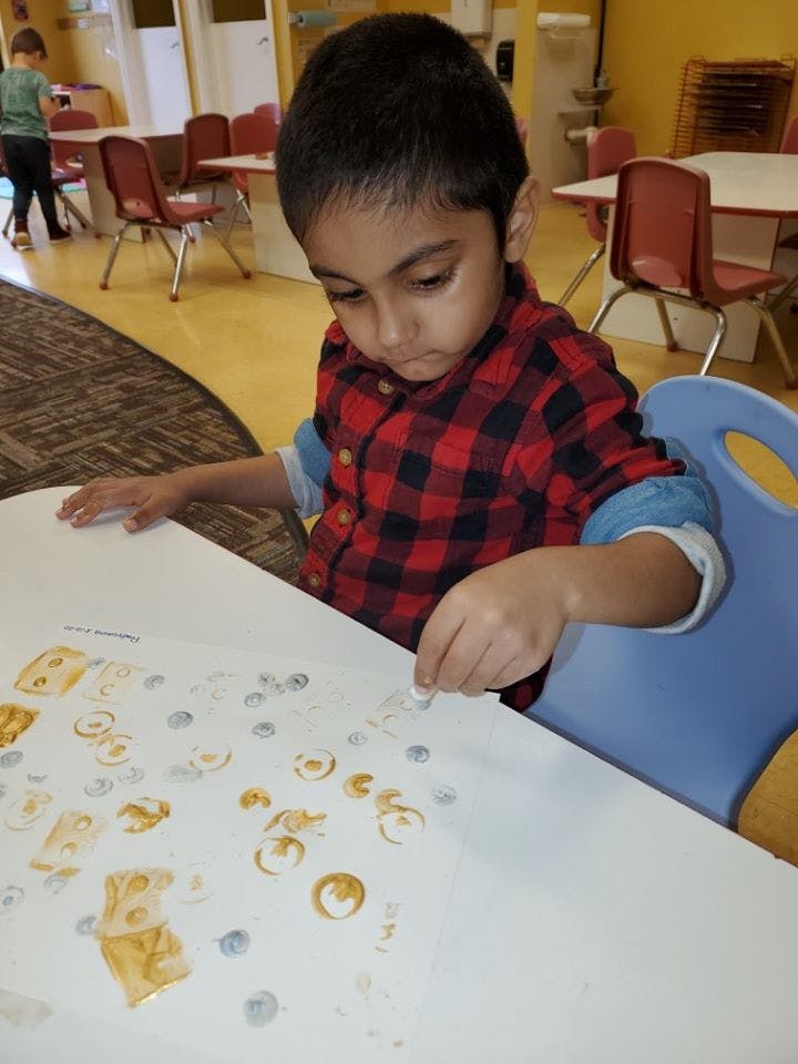 Child sitting at a table making art with stamps