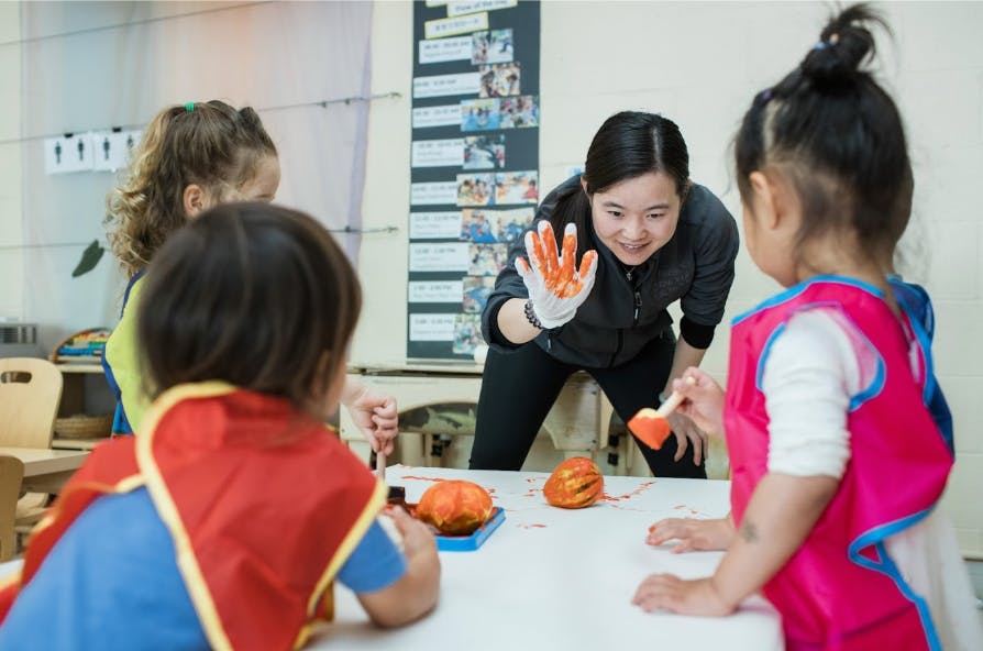 Adult showing painted hand to children at a table