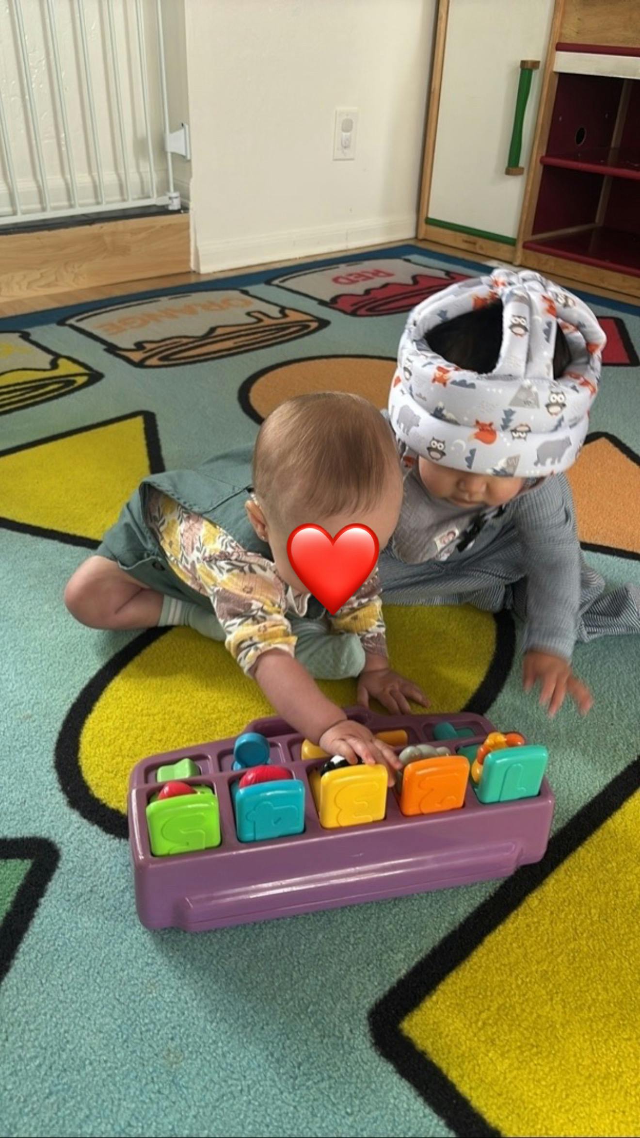 Two children playing with a pop-up toy on a patterned mat