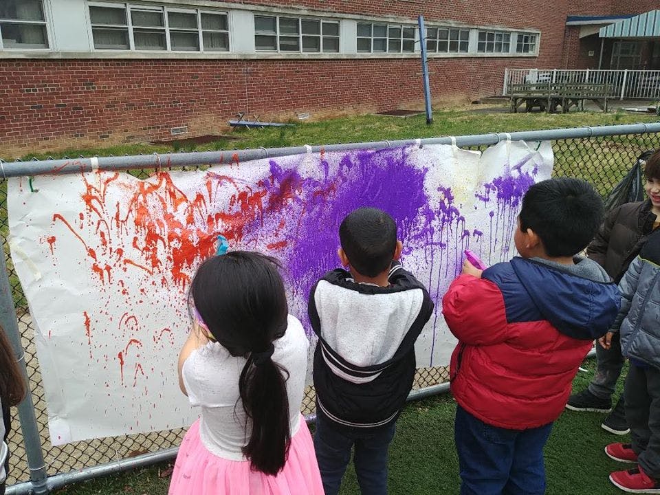 Children painting on a white canvas outdoors