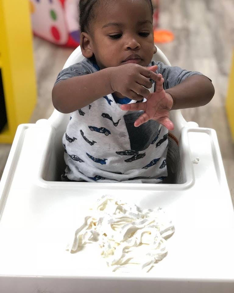 Child in a high chair looking at their hands above food