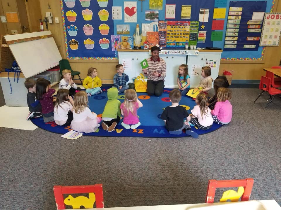 Adult and children sitting on a rug in a classroom