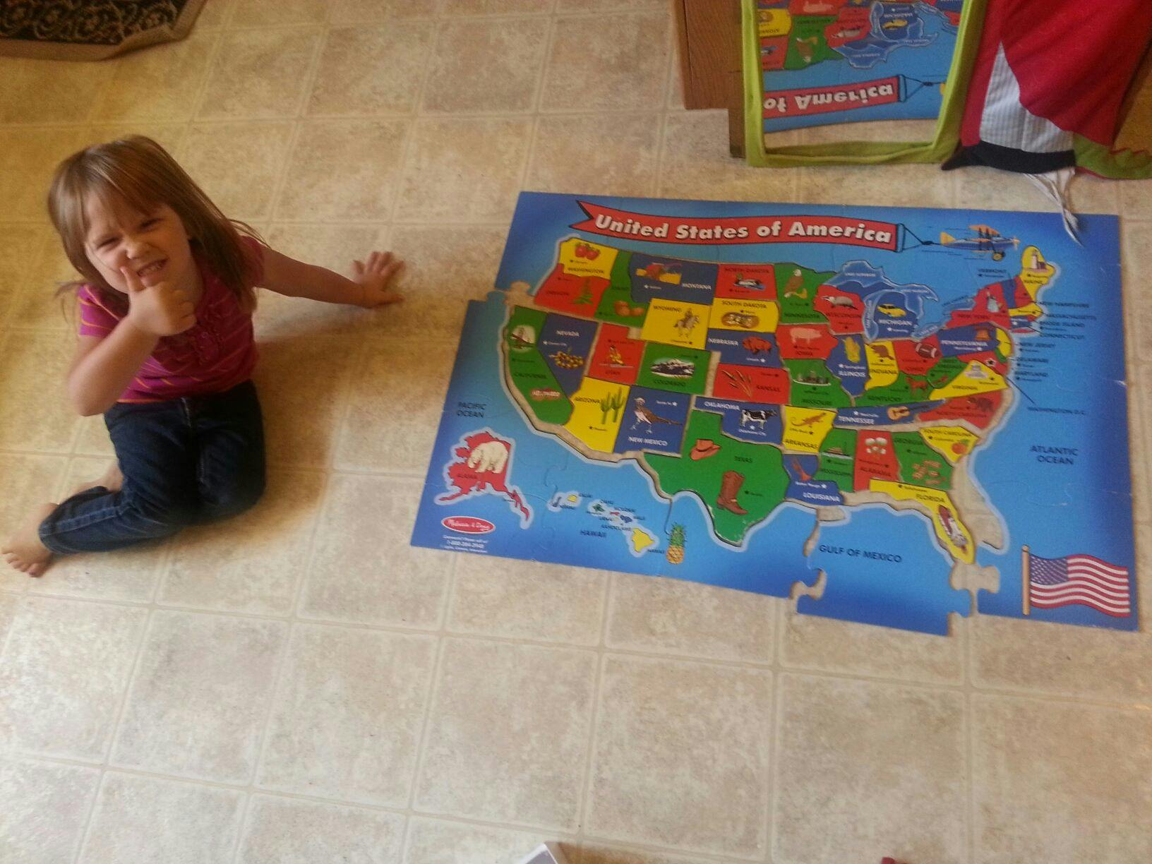 Child kneeling next to a United States of America map puzzle