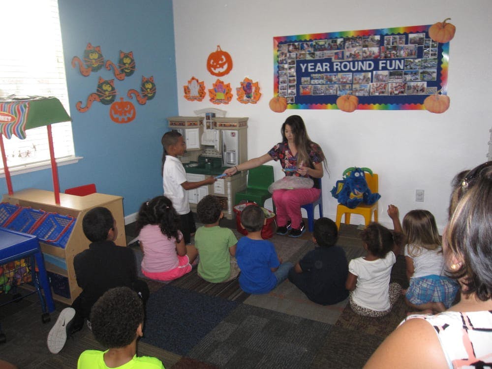 Adult and children in a classroom, adult handing an item to a child