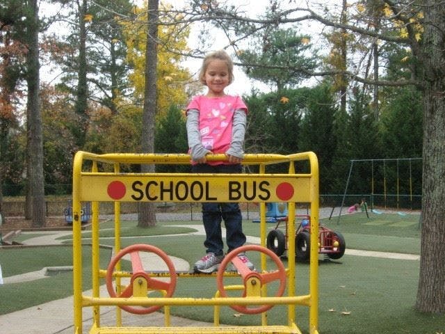 Child standing on a yellow school bus playground structure