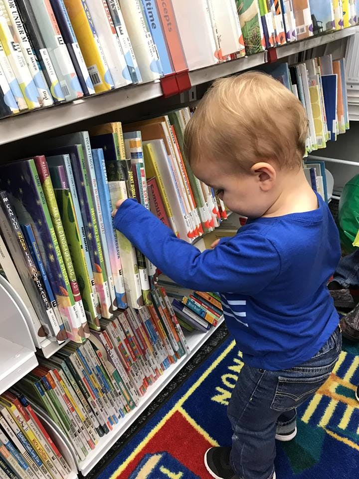 Child looking at books on a library shelf