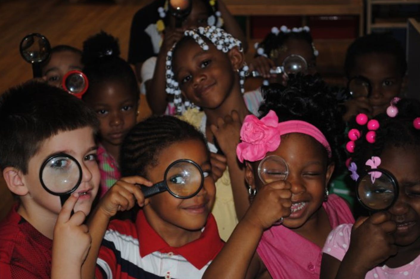 Group of children holding magnifying glasses to their eyes