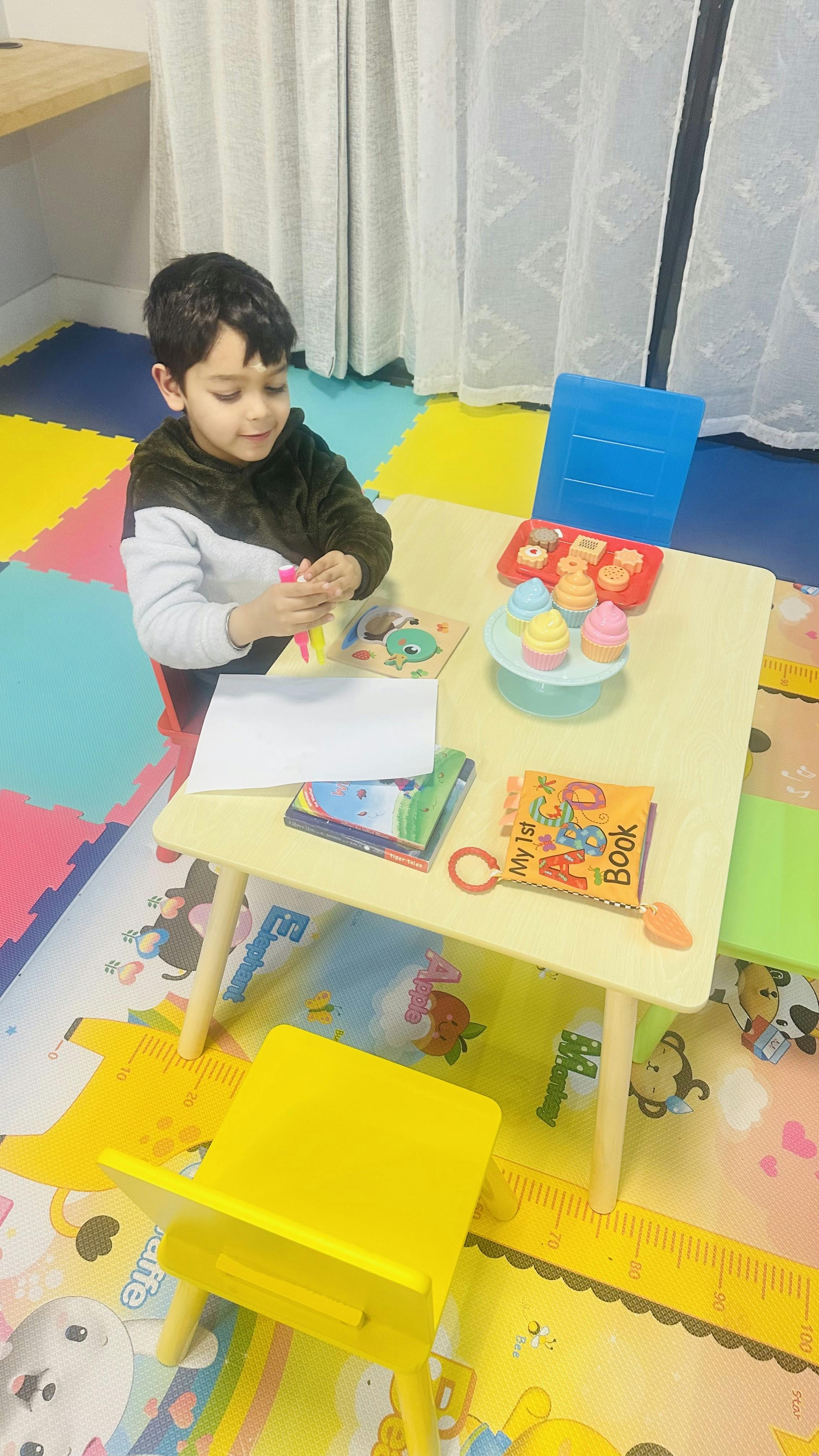 Child sitting at a small table with toys and books
