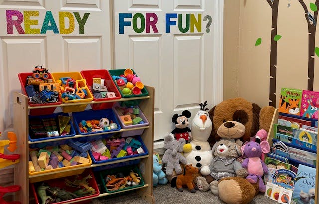 Toy storage shelves and stuffed animals with "READY FOR FUN?" on the wall