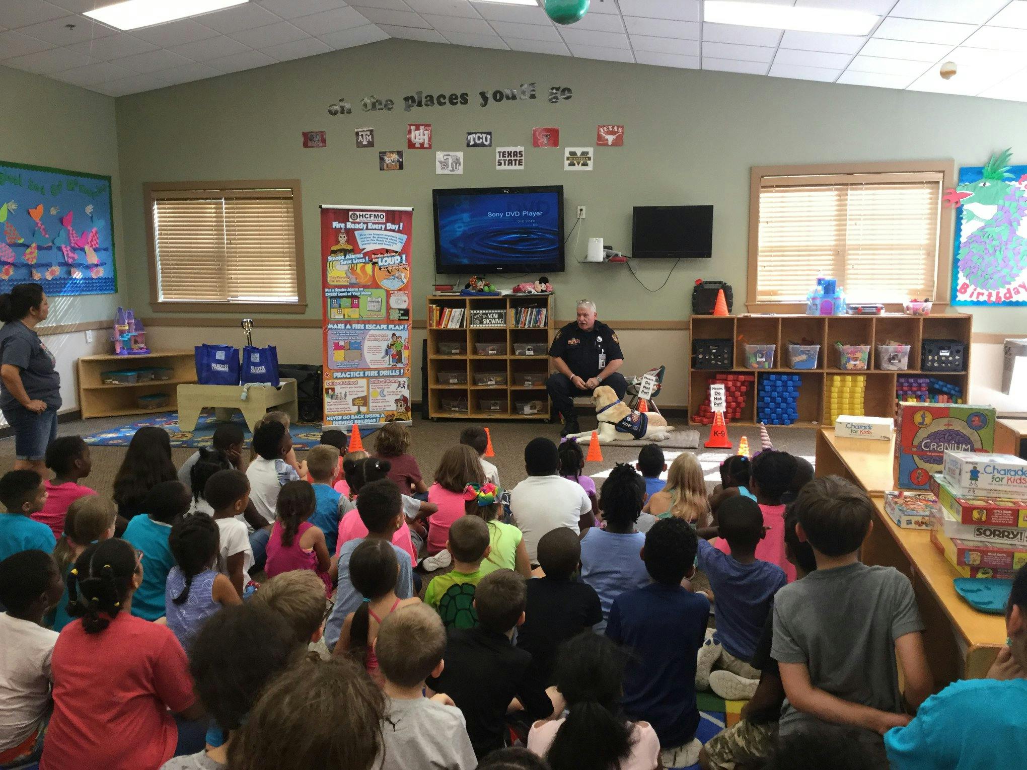 Adult speaking to a group of children seated on the floor in a classroom