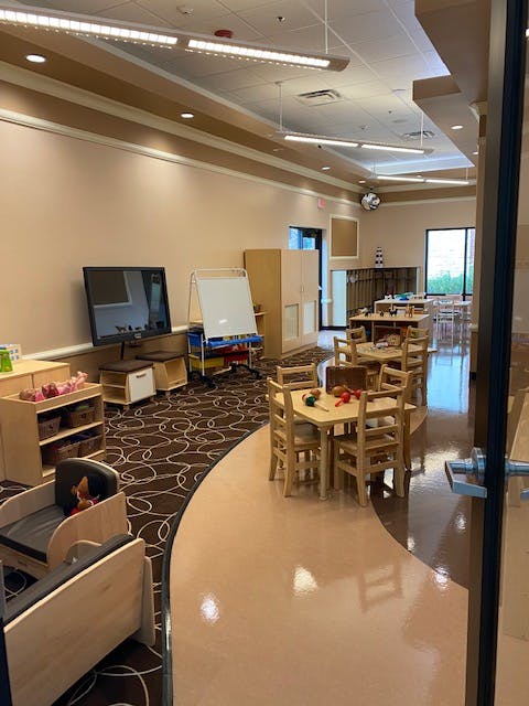 Classroom with small tables and chairs, a television, and a whiteboard