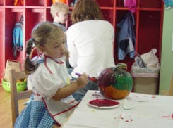 Child painting a pumpkin at a table