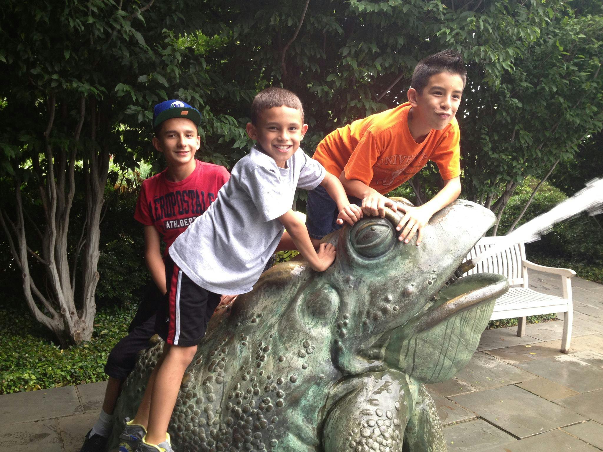 Three children on a frog statue