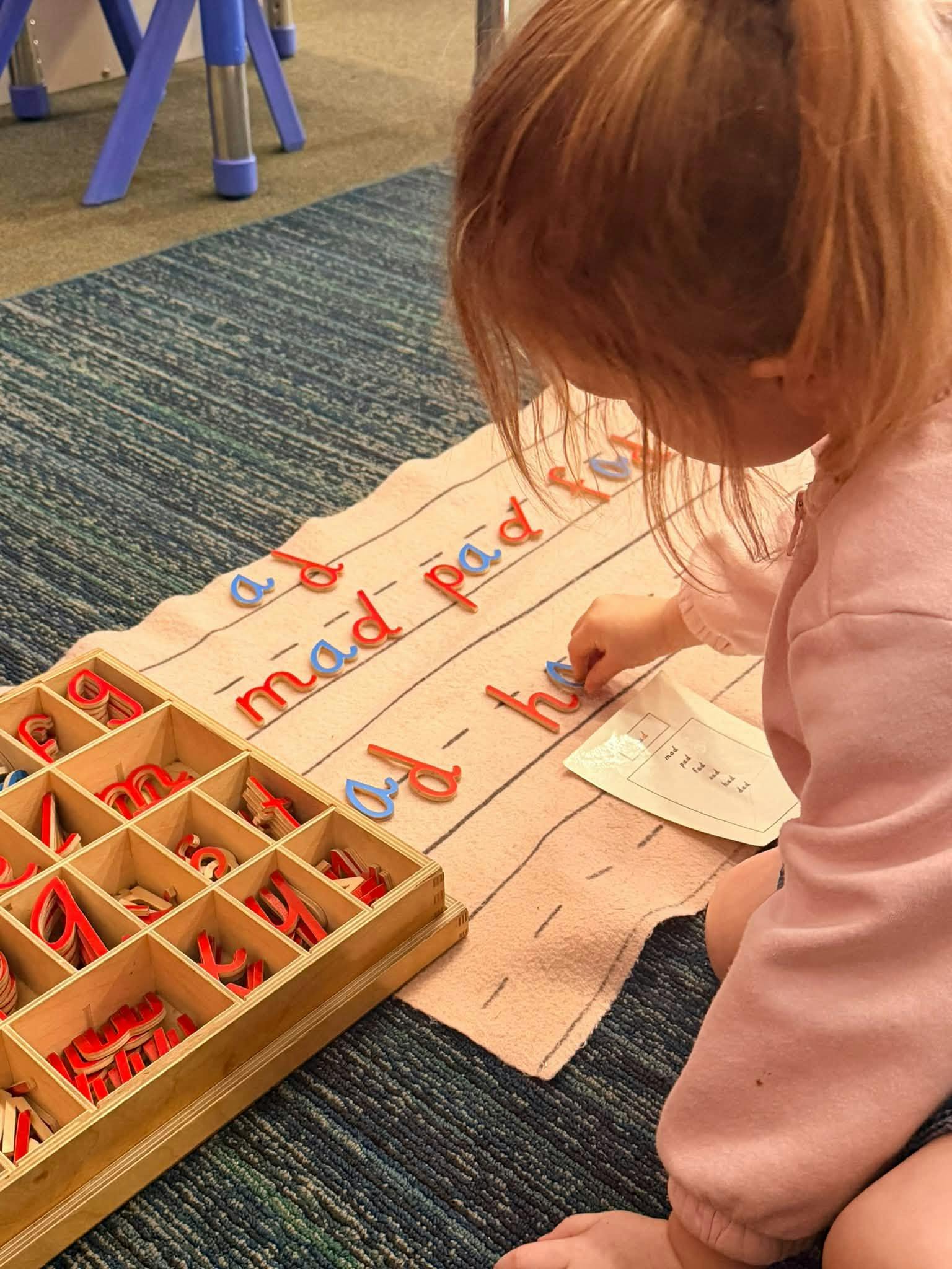 Child arranging wooden letter cutouts to form words on a learning mat