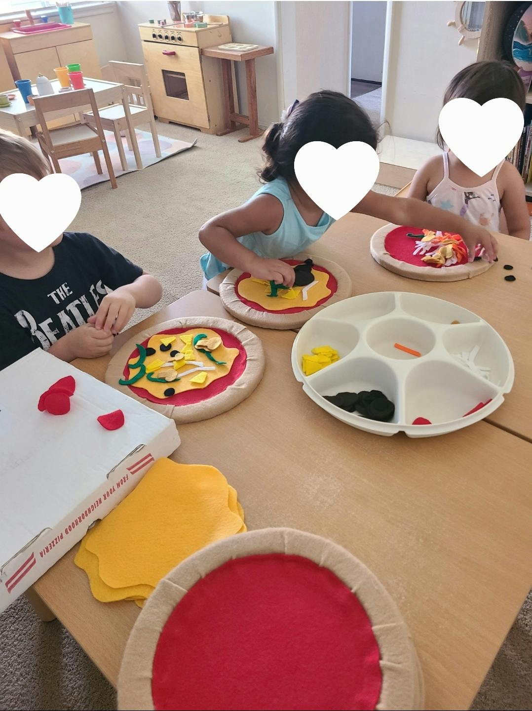 Children playing with felt pizza toys at a table