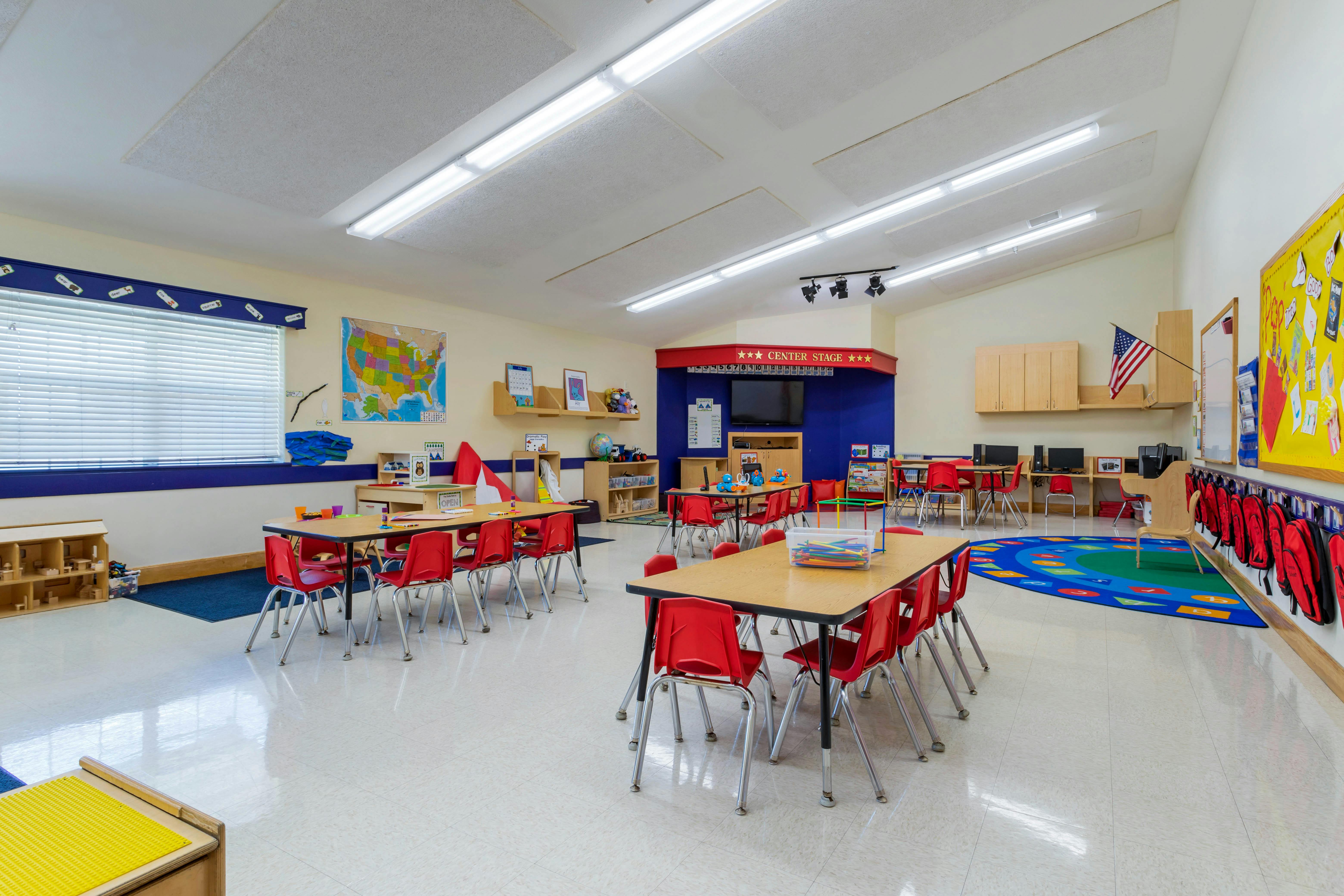 Classroom with tables, red chairs, and a \"Center Stage\" area