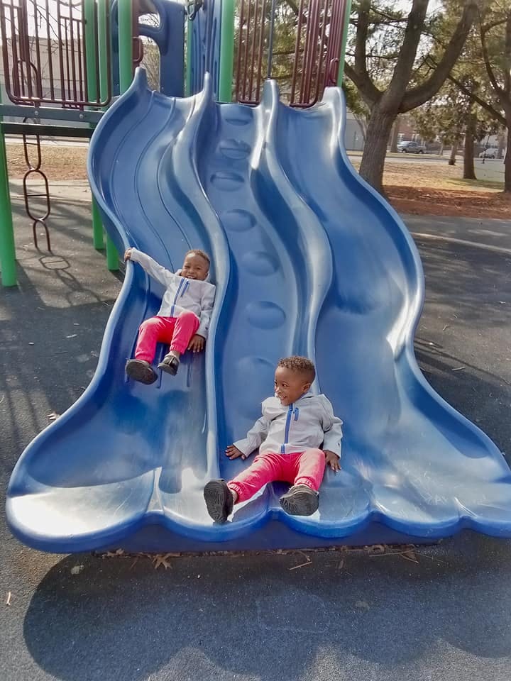 Two children on a blue playground slide