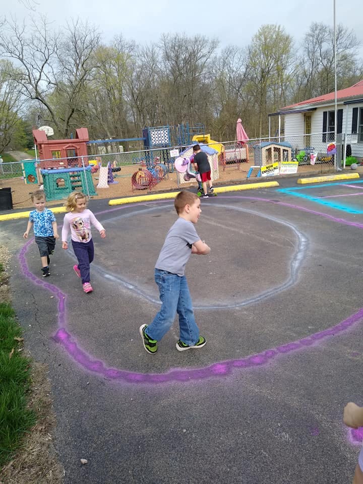 Children running on a playground with chalk drawings on the ground