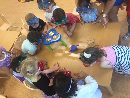 Children wearing goggles looking at a table with a toy on a table