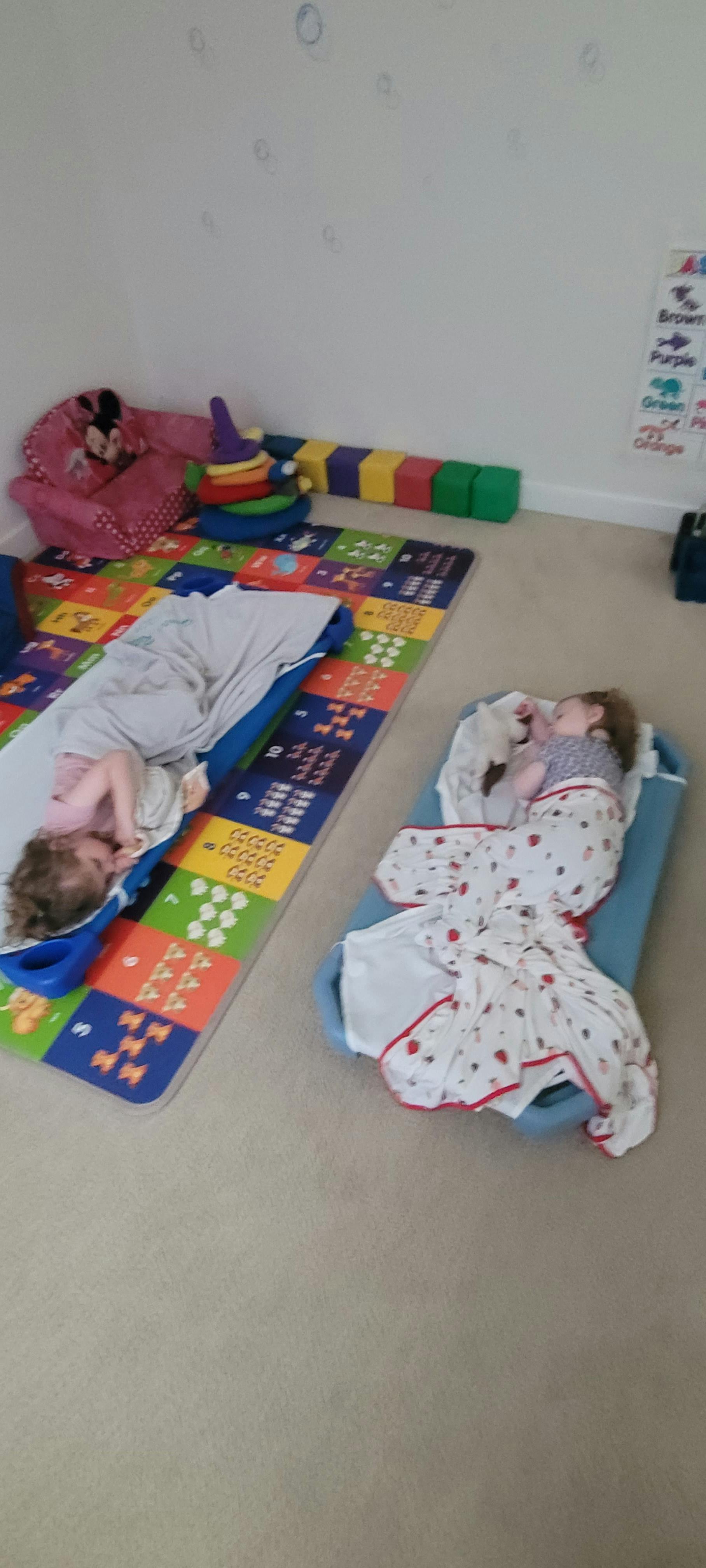 Two children sleeping on mats on the floor