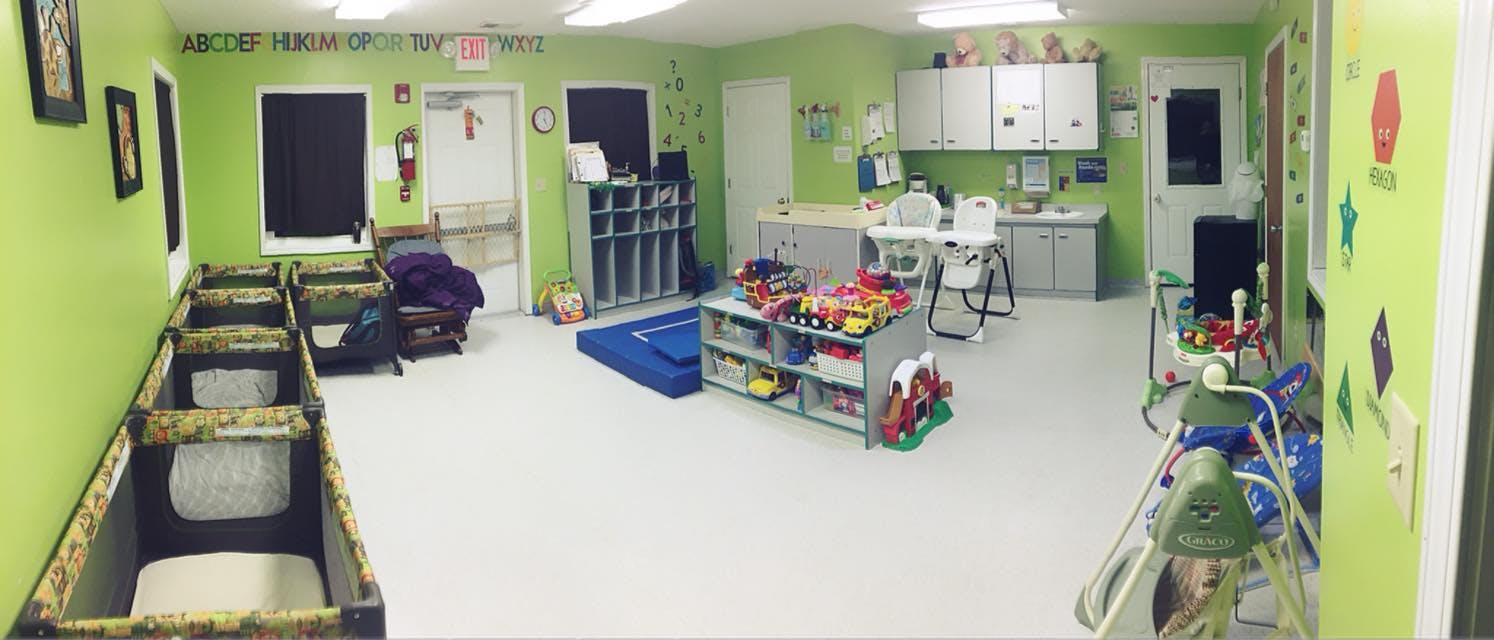 Daycare room with cribs, play mats, and toys