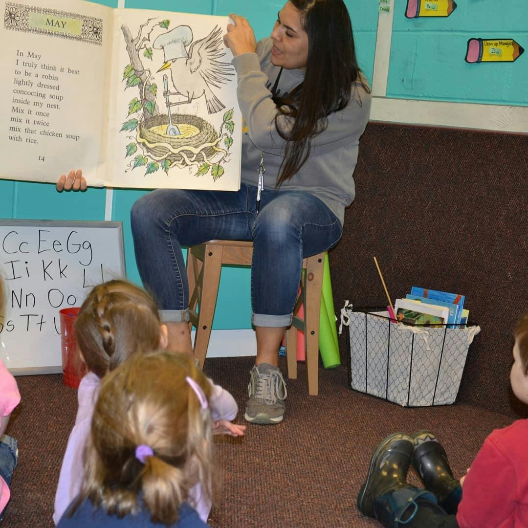 Person reading a book to children in a classroom