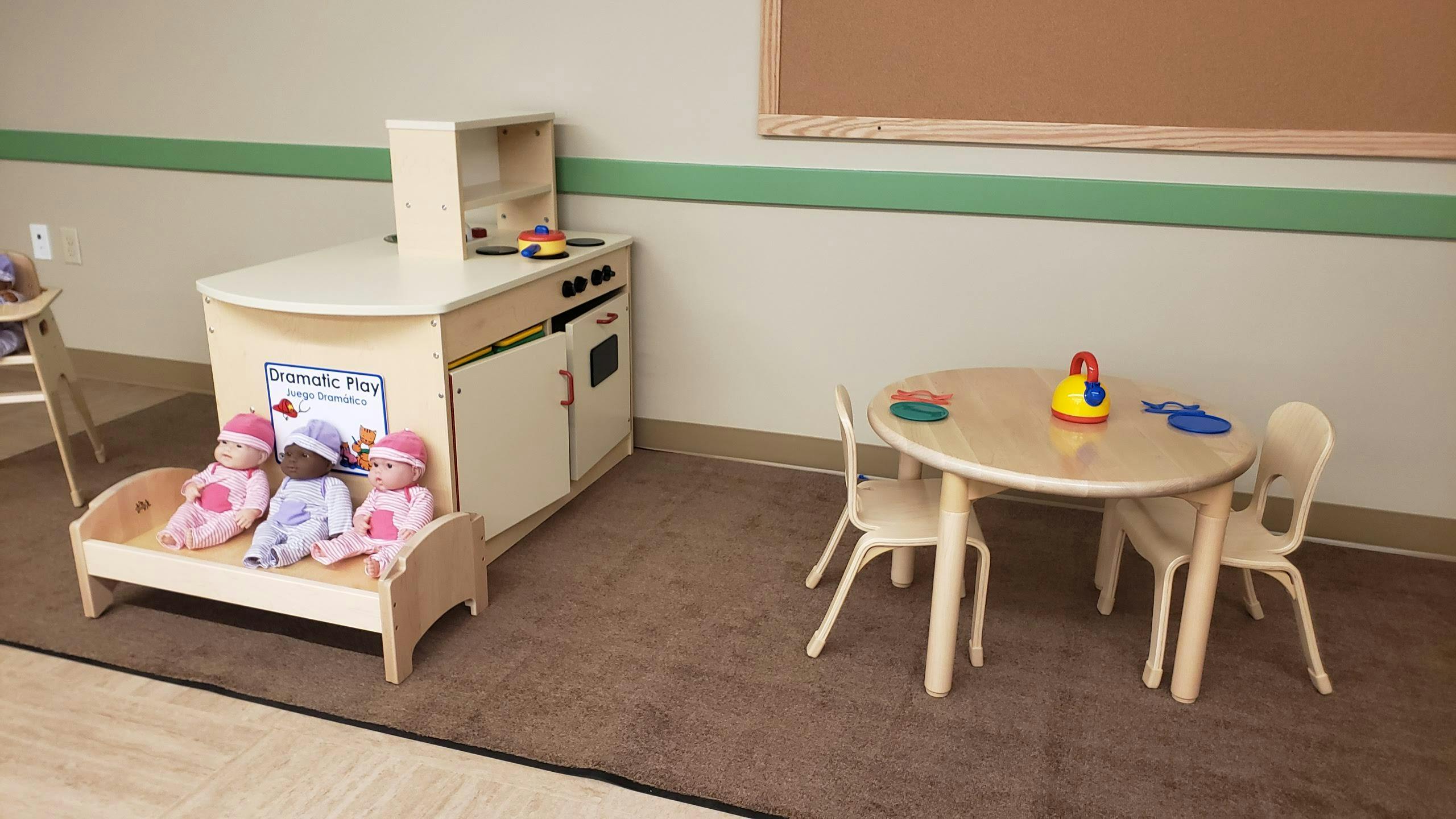 Play kitchen with dolls in a bed and a small table with chairs